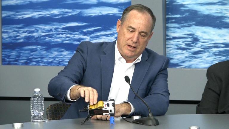 Steve Altemus zeigt mit einem Modell, wie das Landemodul Odysseus auf der Mondoberfläche liegt