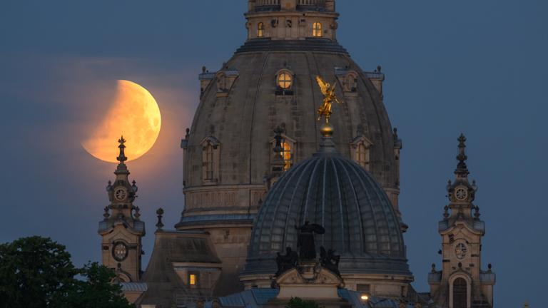 Der Mond geht am Morgen, während einer partiellen Mondfinsternis hinter der Frauenkirche, am 16.05.2022 in Dresden unter.