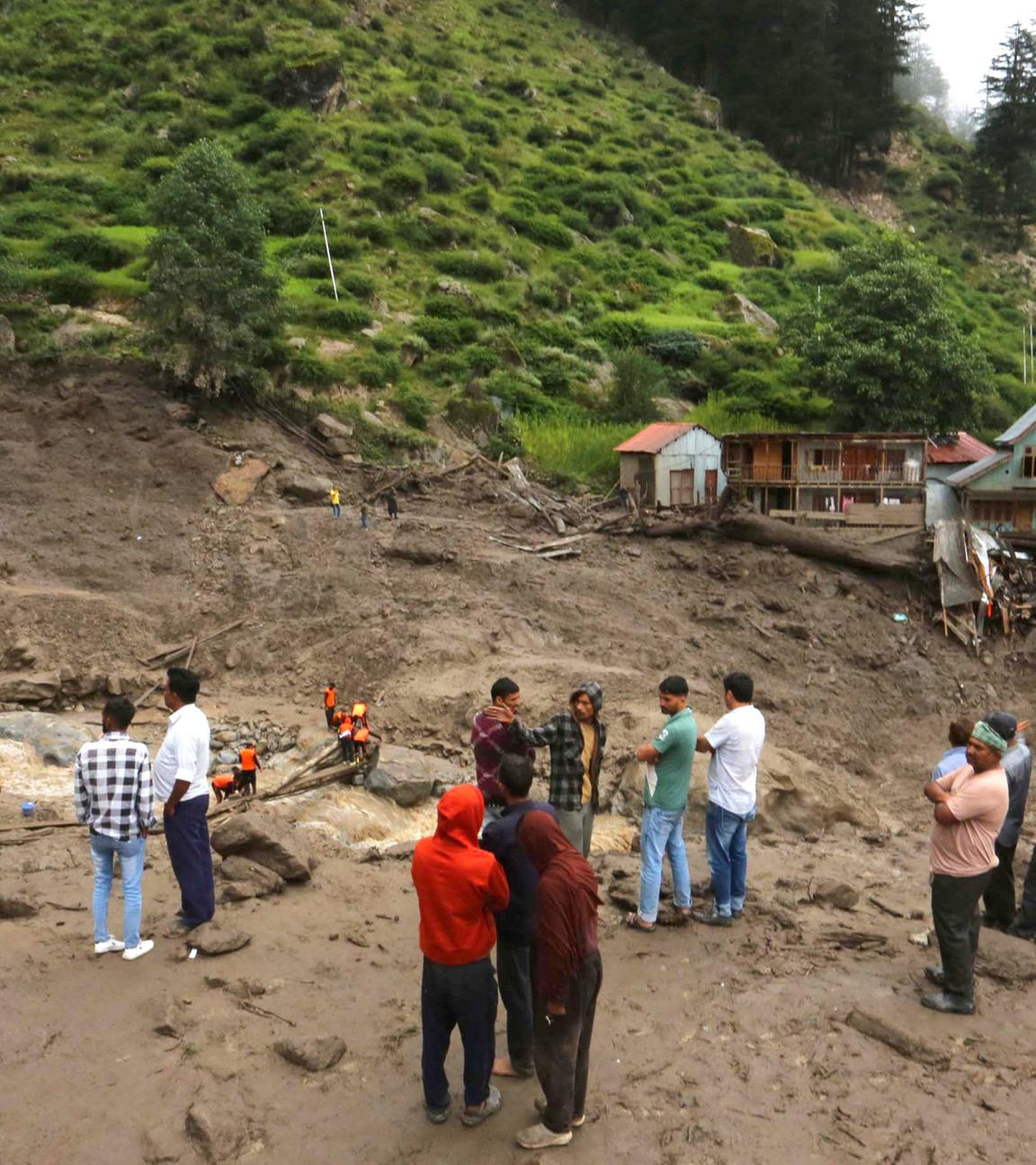  Locals stand at an affected area following a cloudburst at a village in Kishtwar district