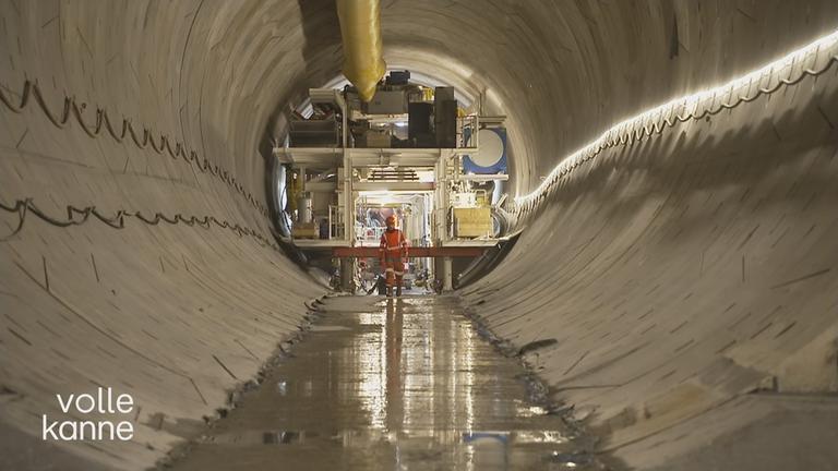 Man sieht einen Tunnel an dessen Ende ein Bauarbeiter an einer Konstruktion steht