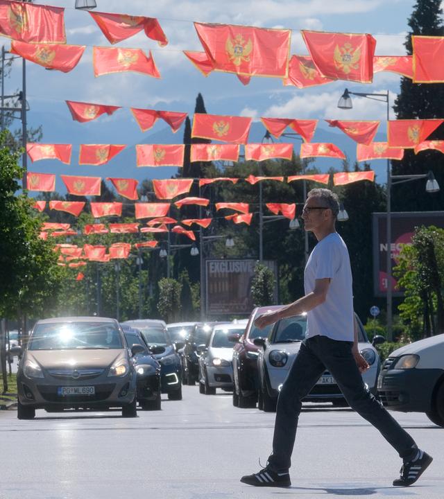 Podgorica, Montenegro: Ein Mann geht über eine Straße, über der viele Nationalflaggen aufgehängt sind. (Archivbild)