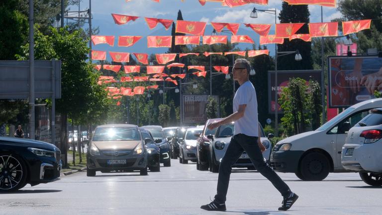 Podgorica, Montenegro: Ein Mann geht über eine Straße, über der viele Nationalflaggen aufgehängt sind. (Archivbild)