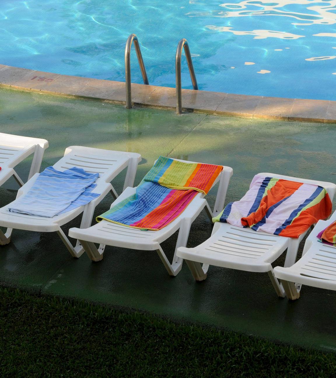 Leere, reservierte Sonnenliegen an einem Hotel-Pool in Spanien.
