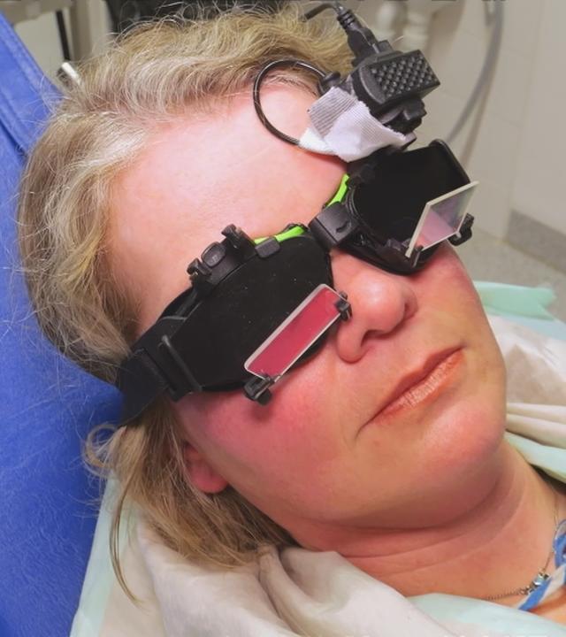 Frau mit medizinischem Instrument auf den Augen auf einer Arztliege