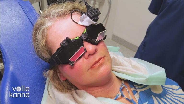 Frau mit medizinischem Instrument auf den Augen auf einer Arztliege