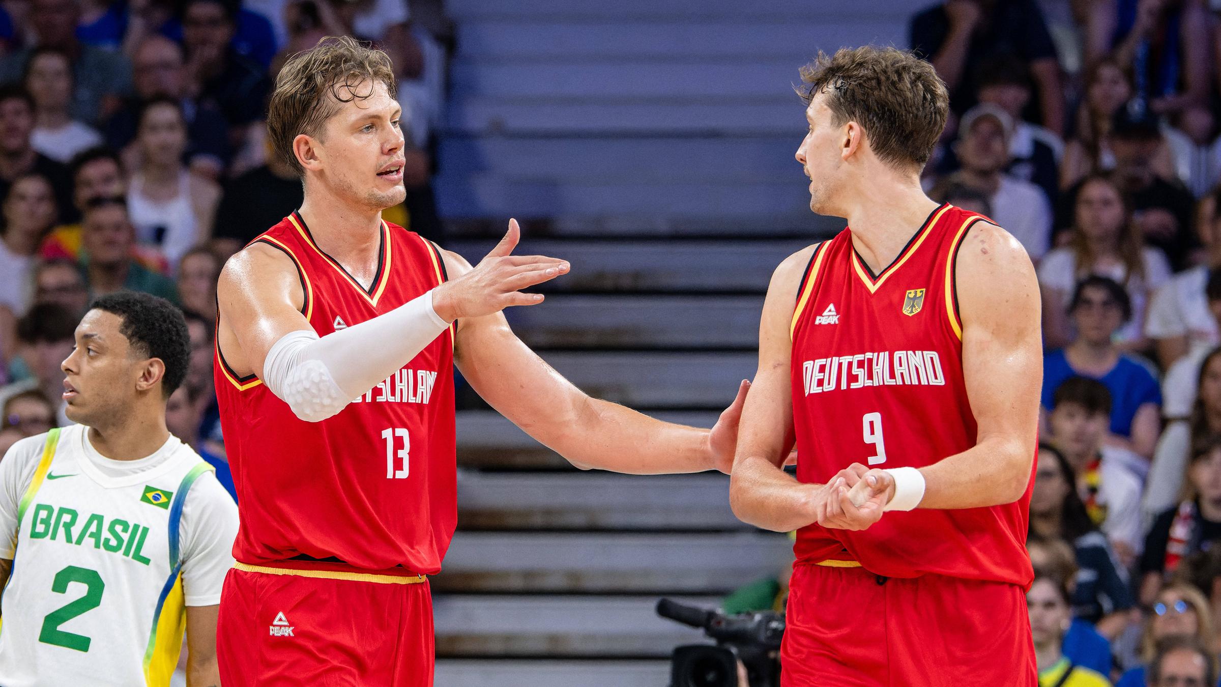 Olympische Spiele Paris 2024: Moritz Wagner (links) und sein Bruder Franz besprechen sich im Vorrundenspiel gegen Brasilien