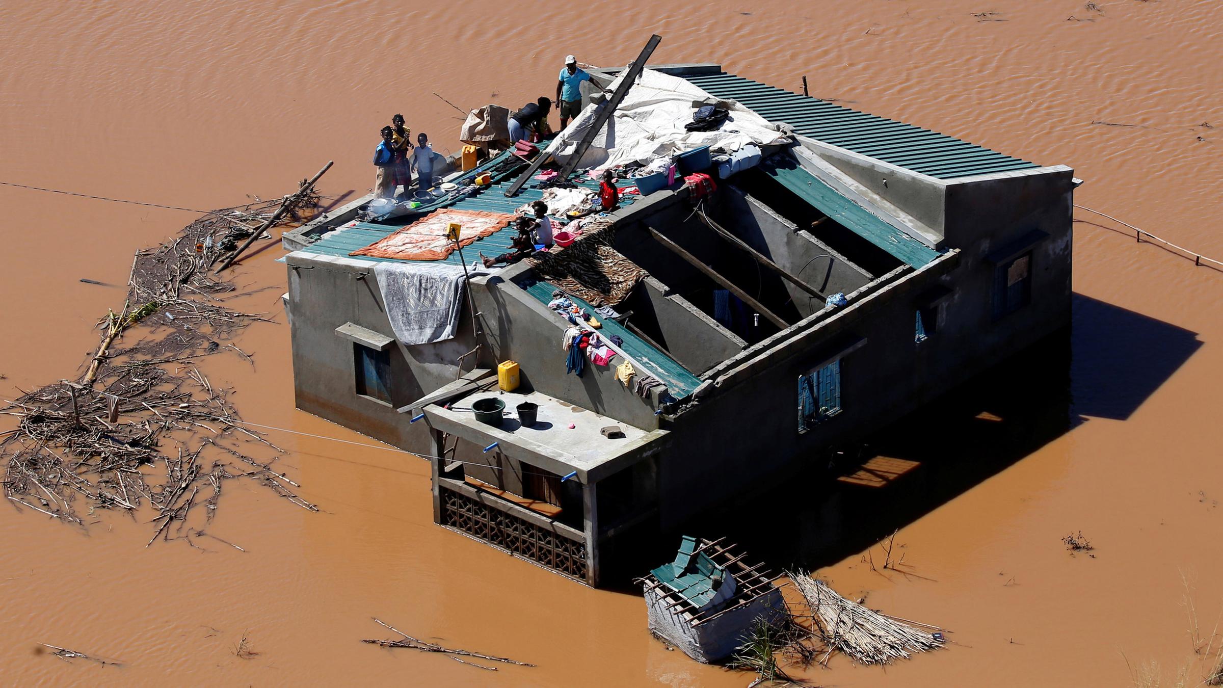 Überschwemmte Landschaft und Menschen, die auf einem Dach Zuflucht suchen am 18.03.2019 in Mosambik