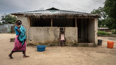 Mosambik, Cabo Delgado: Mutter mit Kind vor Haus