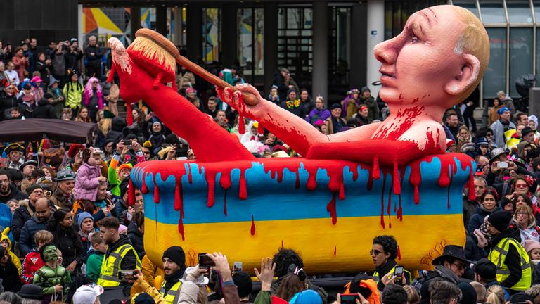 Wladimir Putin nimmt auf einem Motivwagen des Düsseldorfer Rosenmontagsumzuges ein Blutbad als Fastnachtsfigur am 20.02.2023.