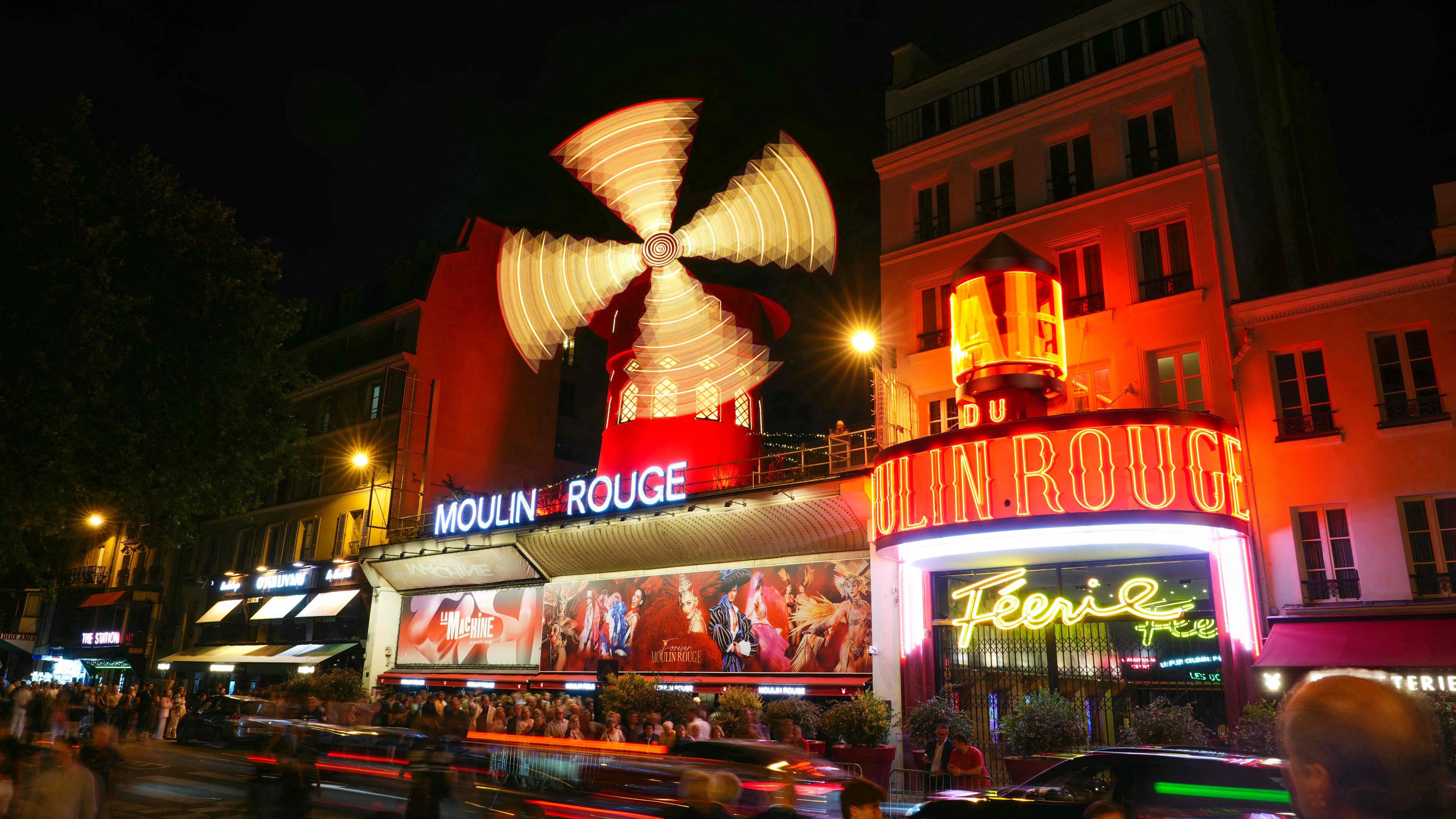Dieses Bild mit Langzeitbelichtung zeigt die neuen Flügel der Windmühle des Moulin Rouge, die sich drehen, während das Kabarett in Paris seine Wiederinbetriebnahme feiert. 