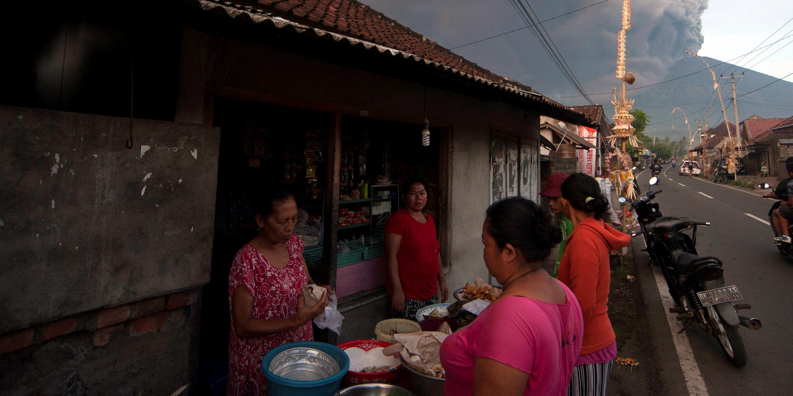 Menschen kaufen Lebensmittel ein, im Hintergrund der Mount Agung auf Bali am 26.11.2017