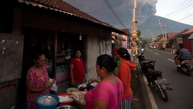Menschen kaufen Lebensmittel ein, im Hintergrund der Mount Agung auf Bali am 26.11.2017