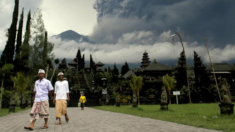 Zwei Hindus im Besakih Tempel auf Bali, im Hintergrund der Mount Agung am 26.11.2017