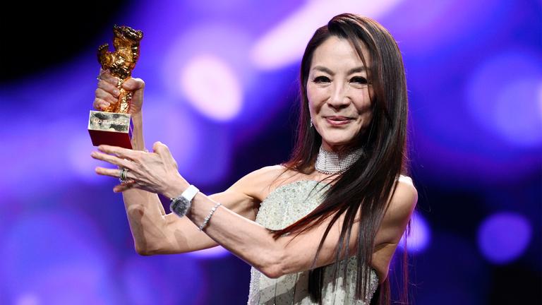 Frau hält Preisstatuette in Form eines goldenen Bären in den Händen und lächelt