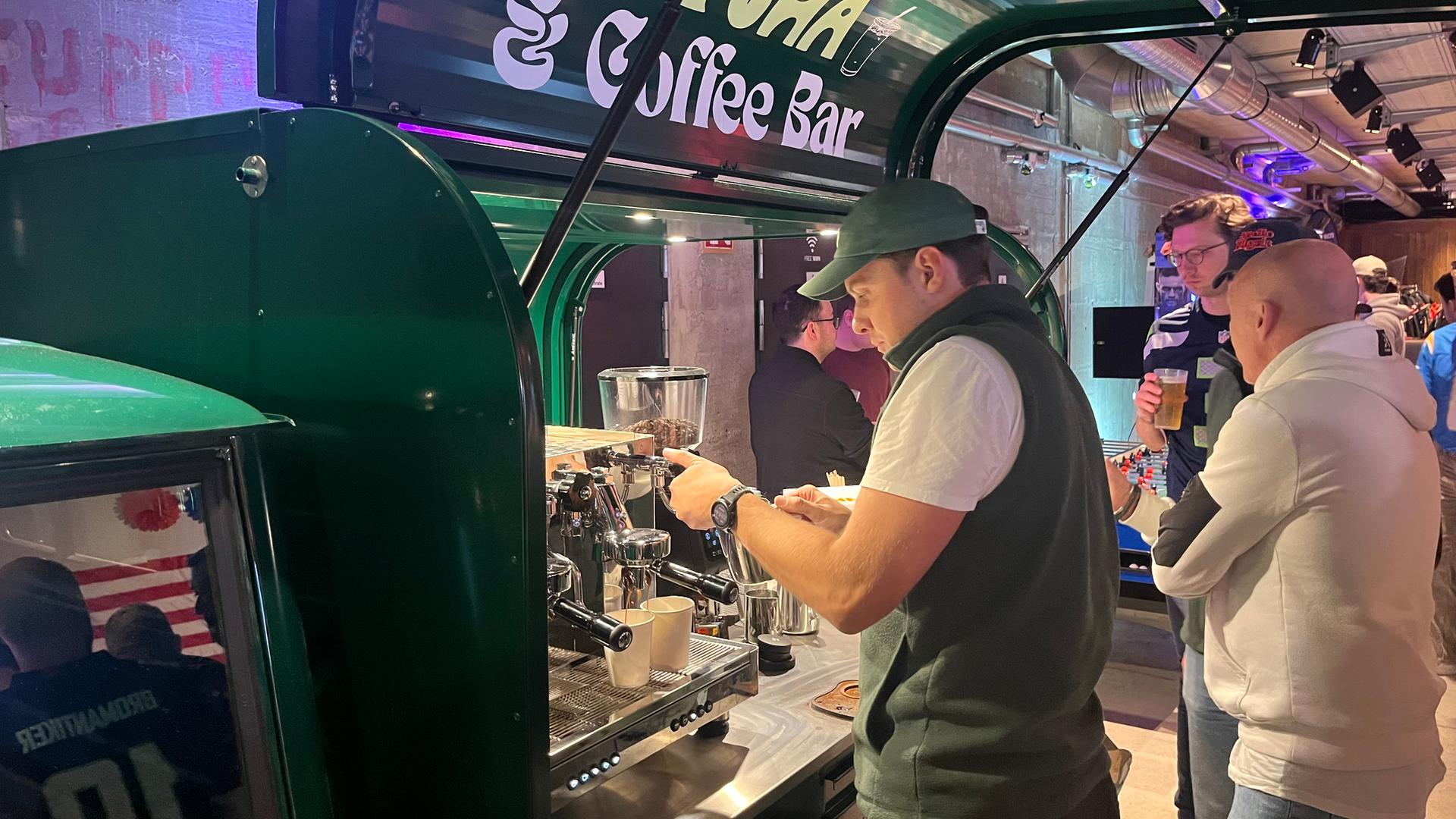 An einem Tuk-Tuk stellt ein Mitarbeiter Kaffee her.