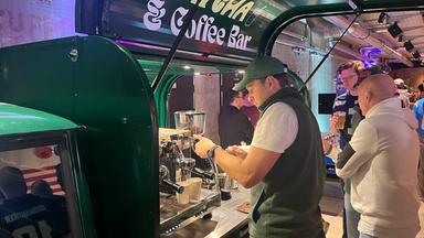 An einem Tuk-Tuk stellt ein Mitarbeiter Kaffee her.