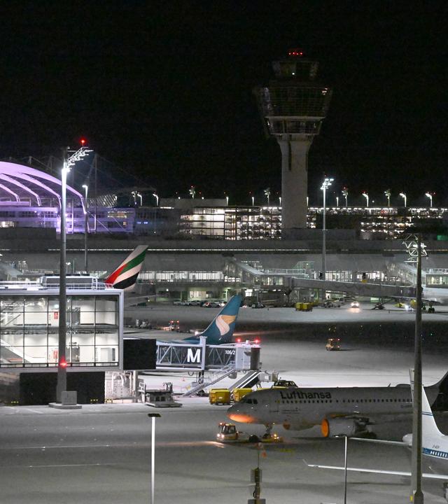 Flugzeuge stehen bei Nacht auf dem Flughafen München.