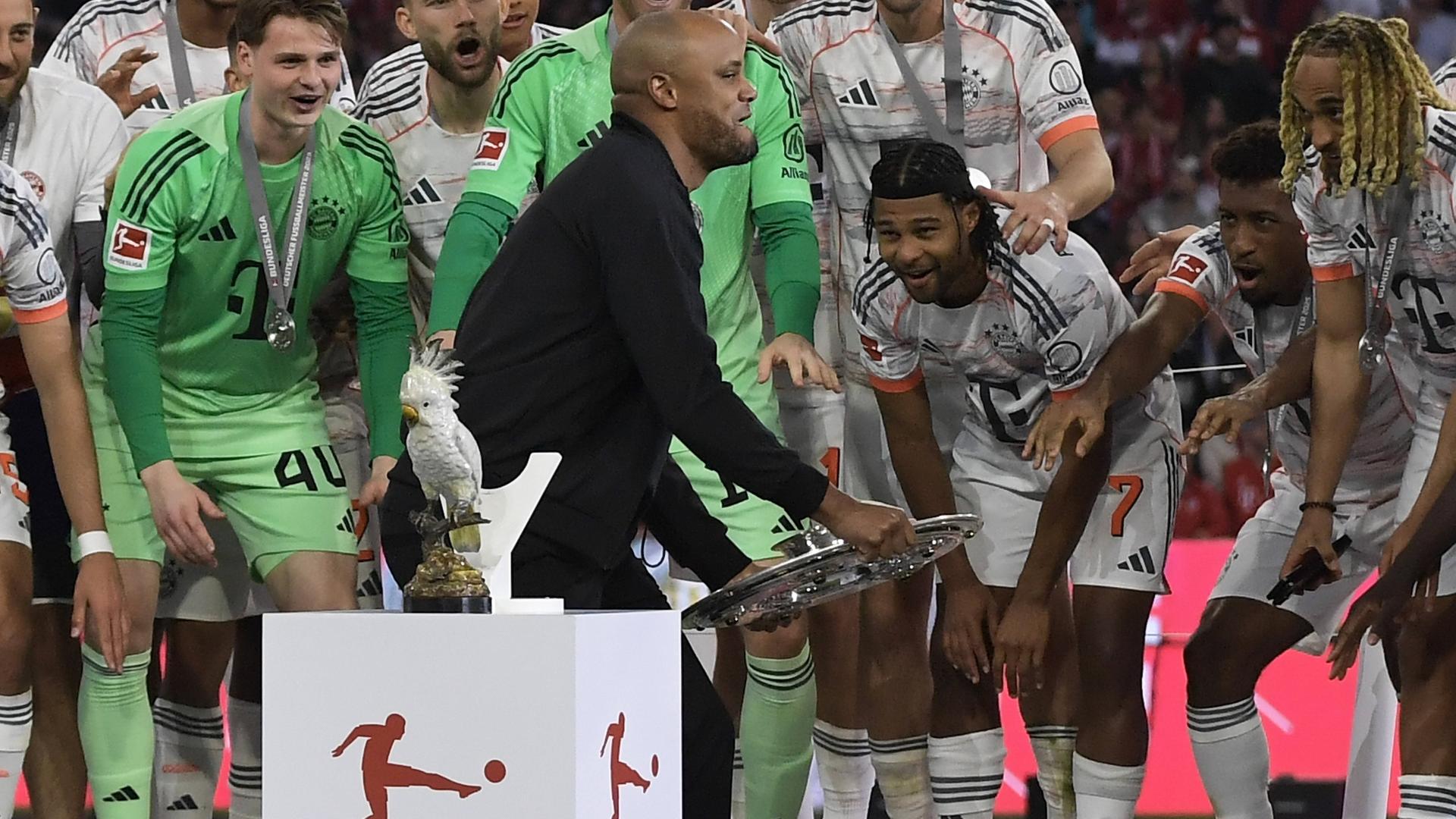 Münchens Trainer Vincent Kompany stellt einen Kakadu beim Podium ab.