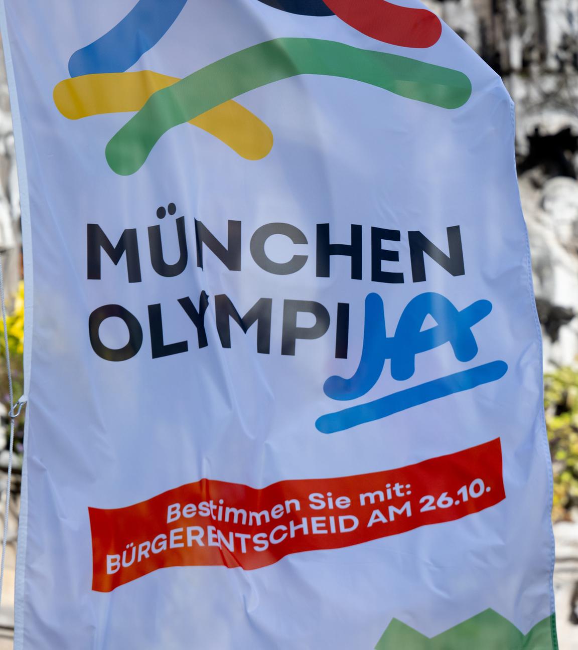 Eine Fahne mit der Aufschrift München OlympiJA weht auf dem Marienplatz vor dem Rathaus.