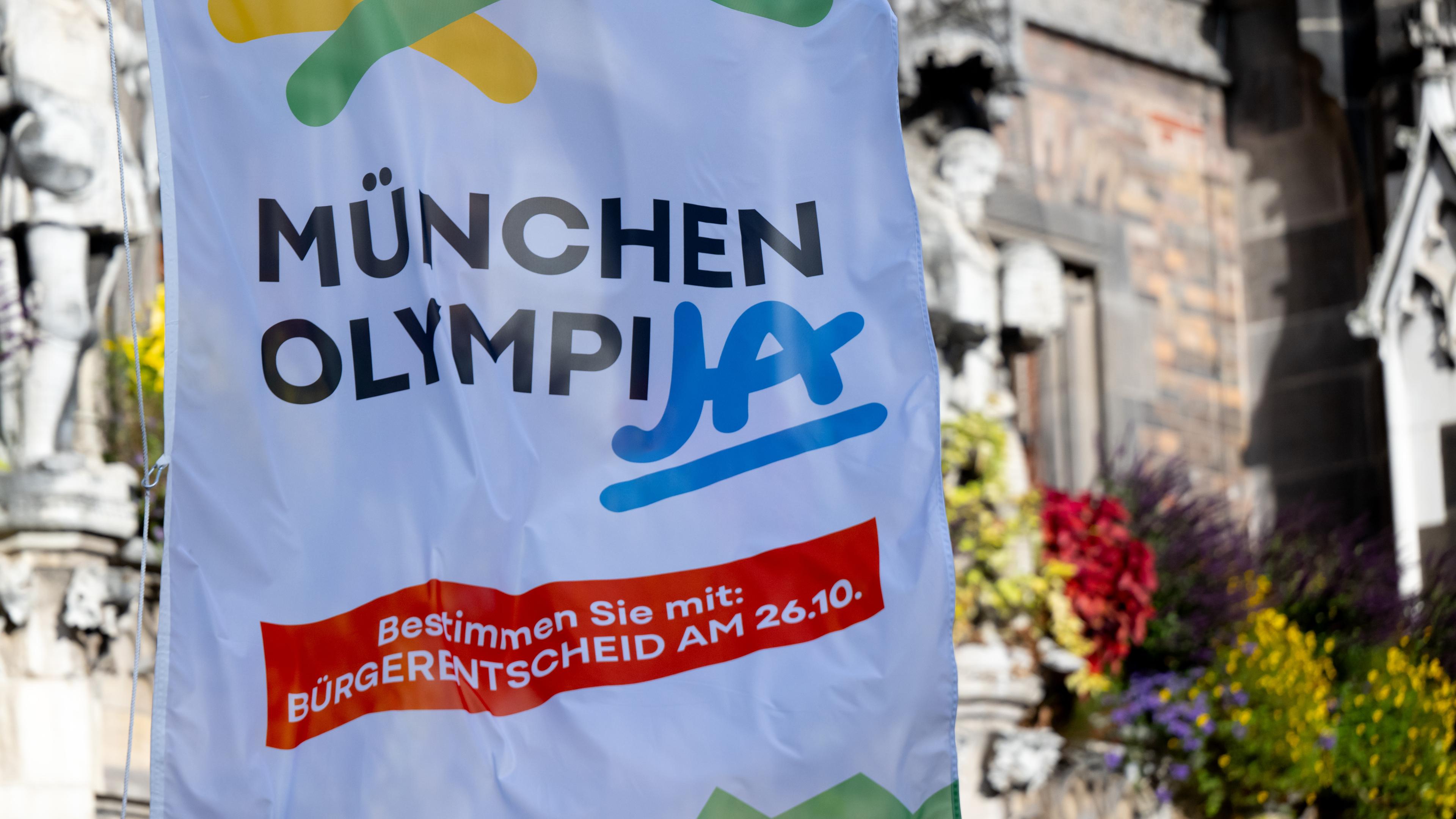 Eine Fahne mit der Aufschrift München OlympiJA weht auf dem Marienplatz vor dem Rathaus.