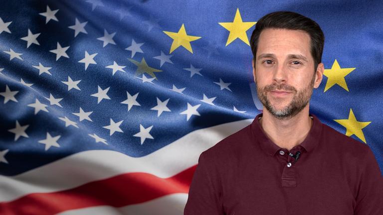 Mirko Drotschmann ist zu sehen, vor einem Hintergrund auf dem sowohl die US-Flagge als auch die EU-Flagge zu erkennen sind