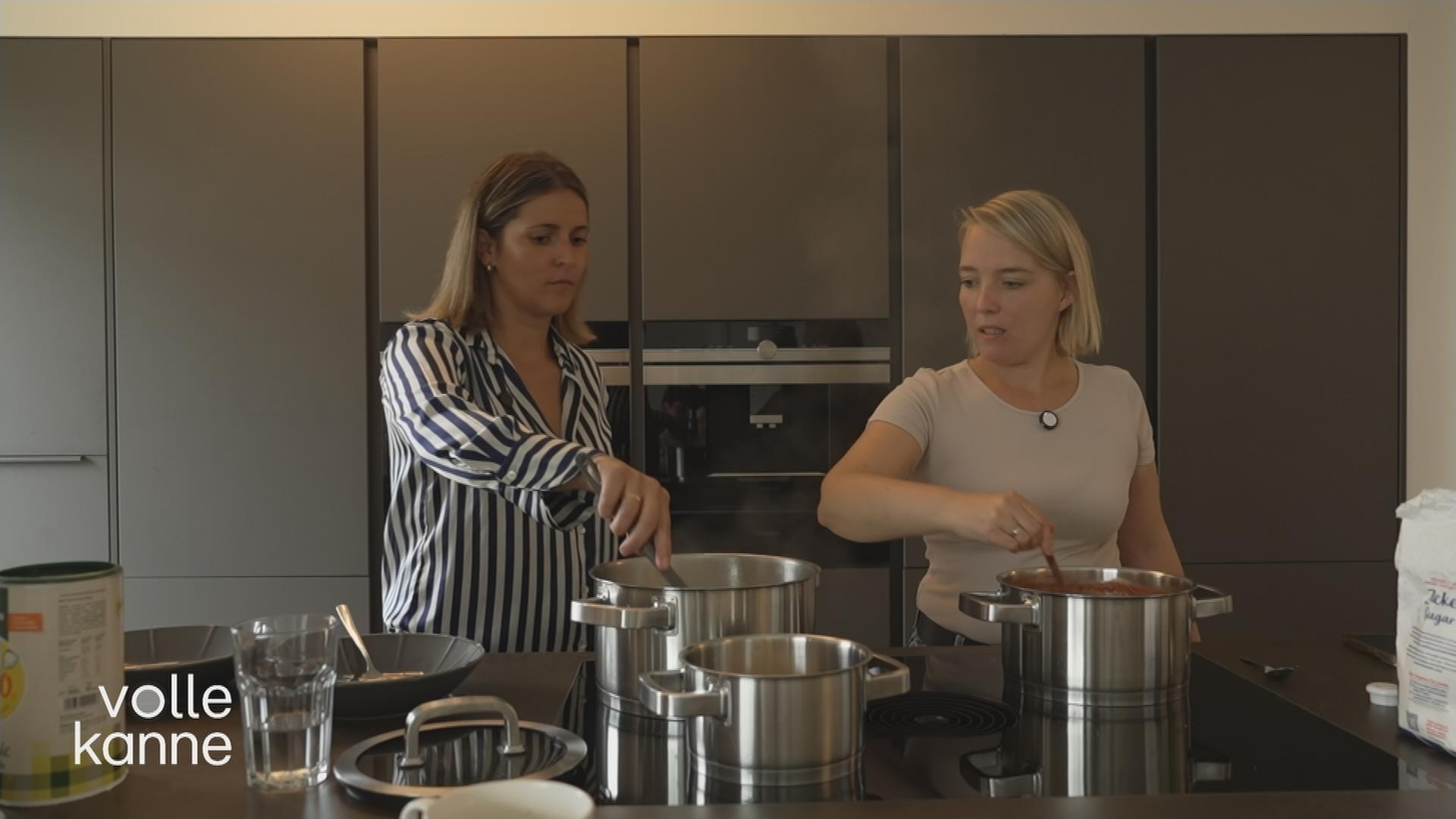 Eine Mütterpflegerin unterstützt eine junge Mutter beim Kochen