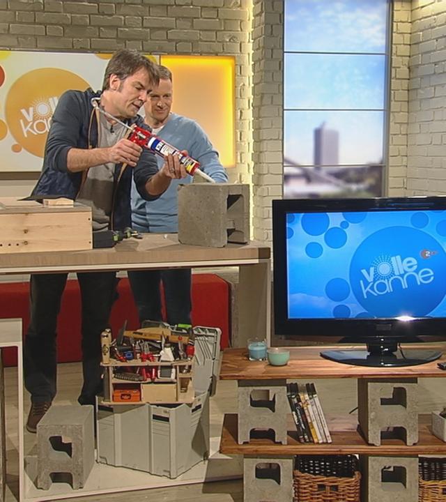 Mick Wewers und Carsten Rüger bauen einen Fernsehschrank im Studio.