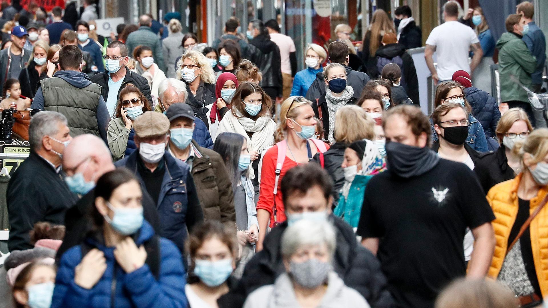 Passanten in einer Fußgängerzone mit Mundschutz