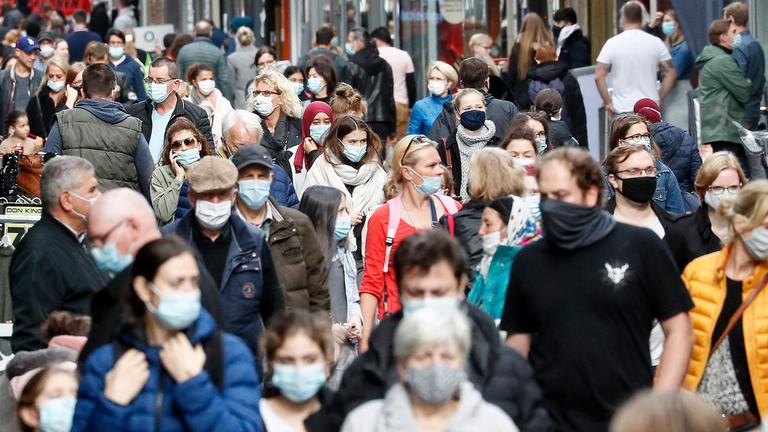 Passanten in einer Fußgängerzone mit Mundschutz