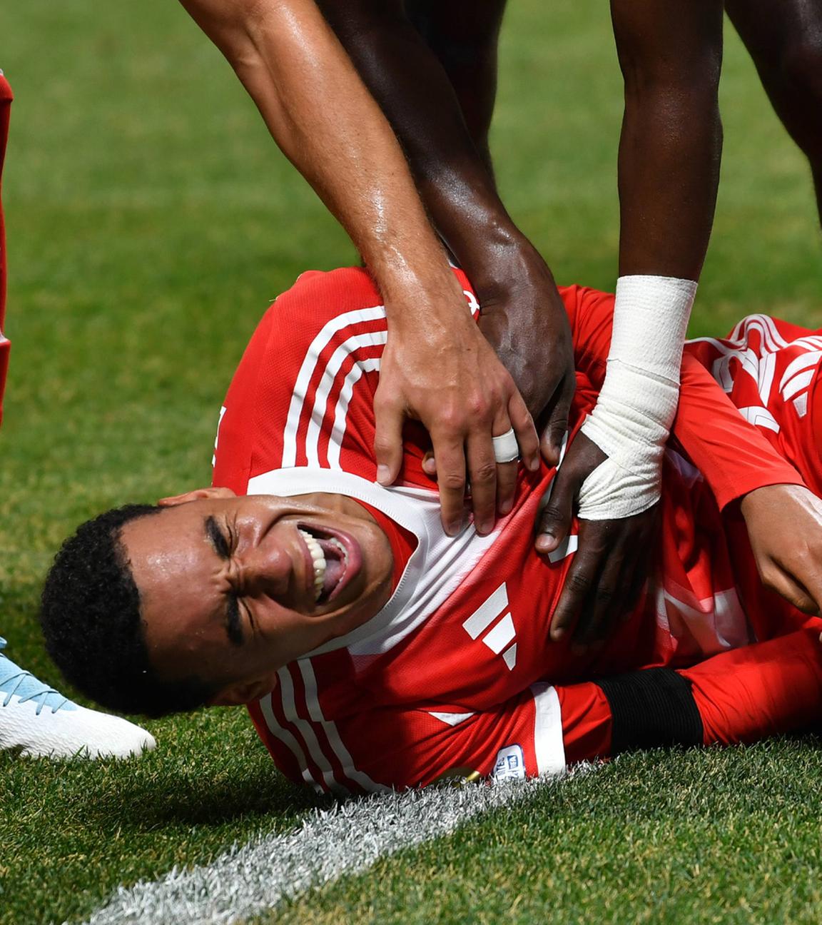 Jamal Musiala von FC Bayern München liegt nach seiner Beinverletzung am Boden. 