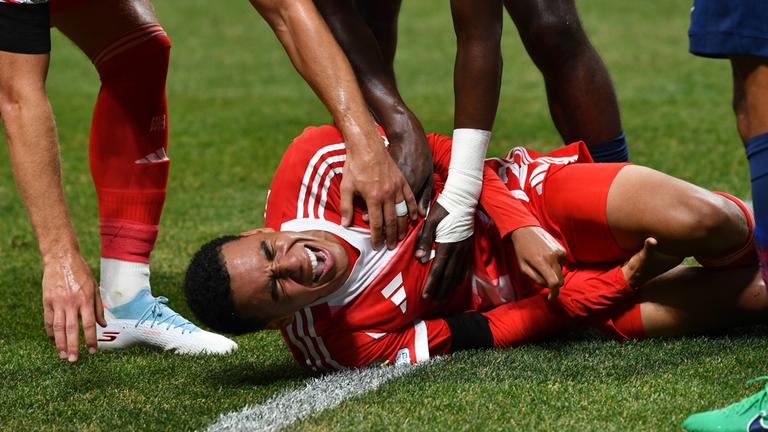 Jamal Musiala von FC Bayern München liegt nach seiner Beinverletzung am Boden. 