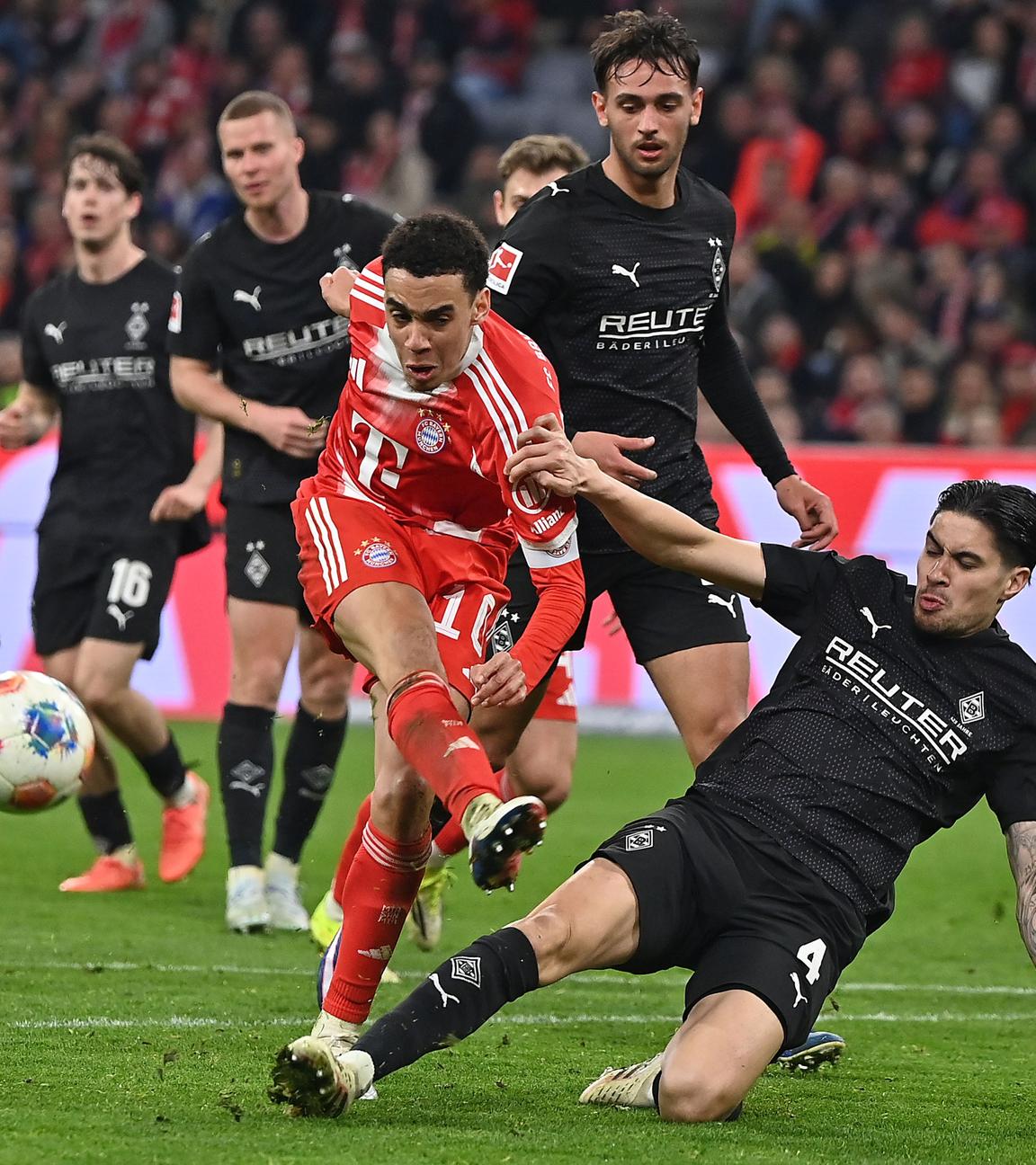 Gladbachs Verteidiger Kevin Diks grätscht im Zweikampf in Bayerns offensiven Mittelfeldspieler Jamal Musiala rein