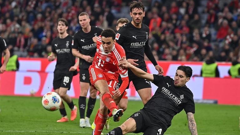 Gladbachs Verteidiger Kevin Diks grätscht im Zweikampf in Bayerns offensiven Mittelfeldspieler Jamal Musiala rein