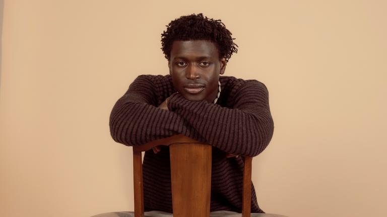 Man sieht einen Mann der auf einem Stuhl sitzen.