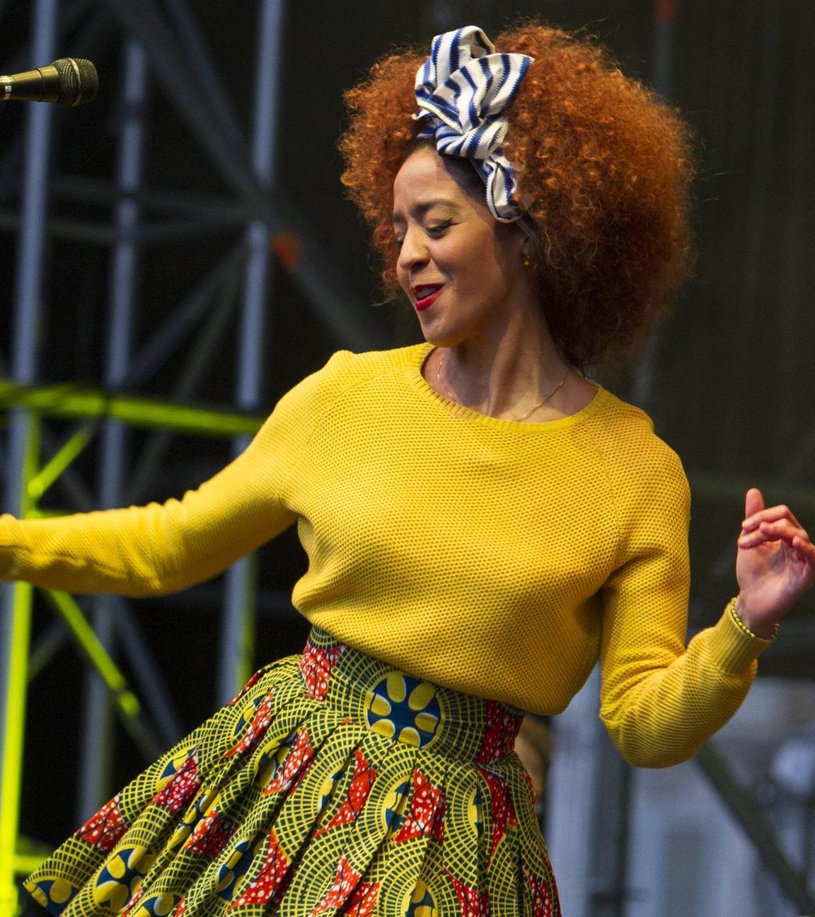 Eine Frau, die einen gelben Pullover trägt, tanzt auf einer Bühne.