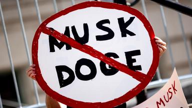 Ein Demonstrant hält ein Plakat mit einem Verkehrsverbotsschild mit der Aufschrift 'Musk DOGE' während einer Kundgebung gegen die Politik von US-Präsident Trump