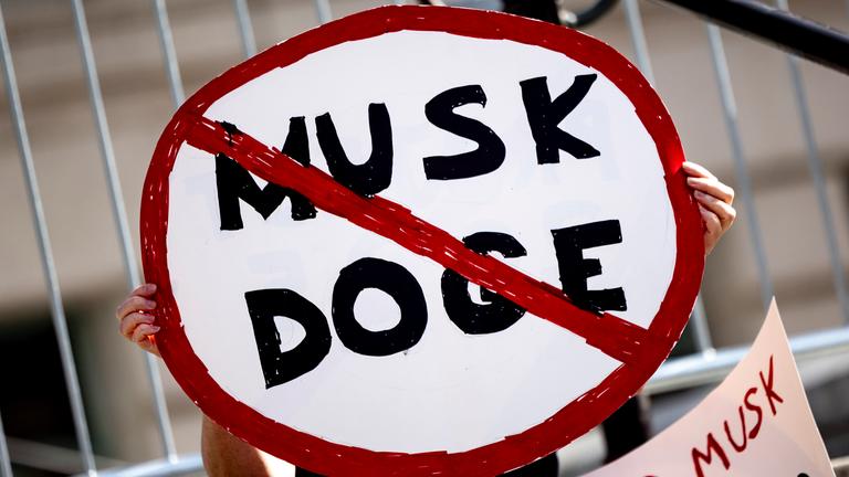 Ein Demonstrant hält ein Plakat mit einem Verkehrsverbotsschild mit der Aufschrift 'Musk DOGE' während einer Kundgebung gegen die Politik von US-Präsident Trump