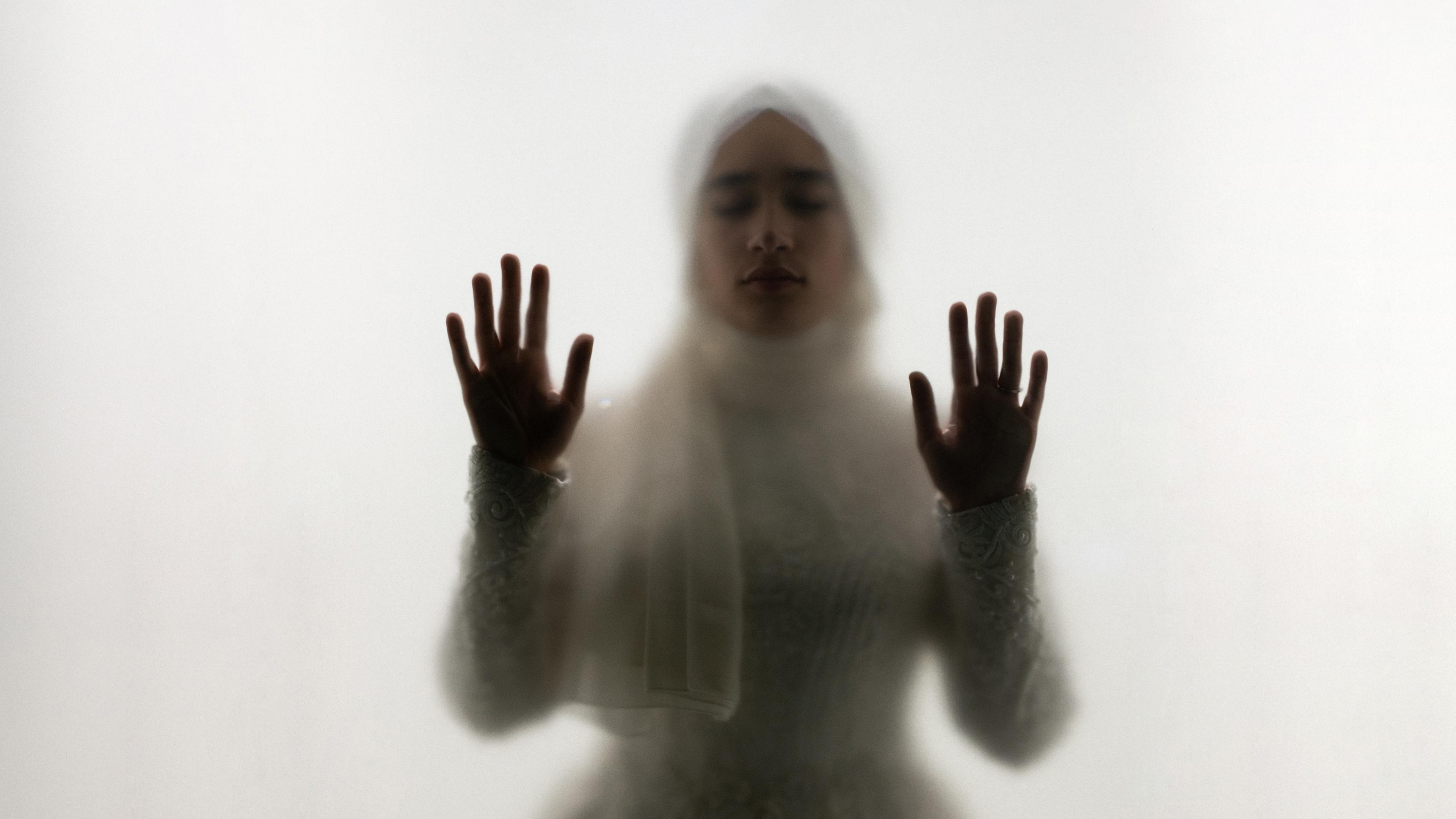 Muslimische Frau steht hinter Glas