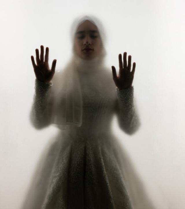 Muslimische Frau steht hinter Glas