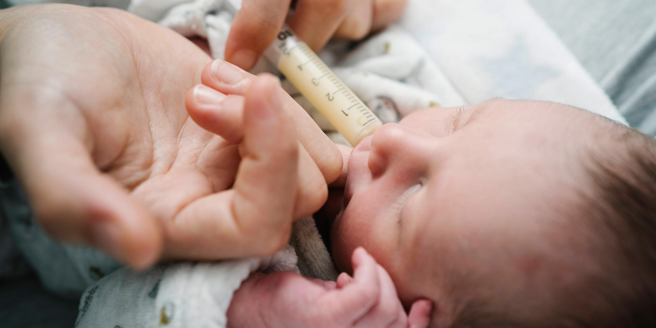 Mutter füttert ih Baby mit einer Spritze
