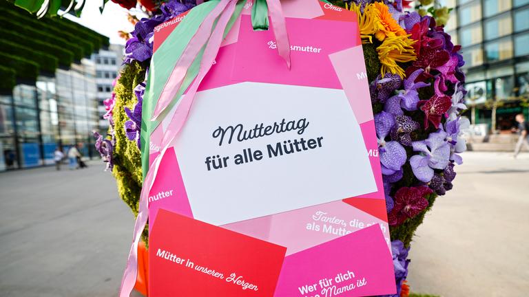 Nordrhein-Westfalen, Düsseldorf: Ein Schild mit der Aufschrift "Muttertag für alle Mütter" ist an einer riesigen Vase mit über 800 Blumen befestigt.