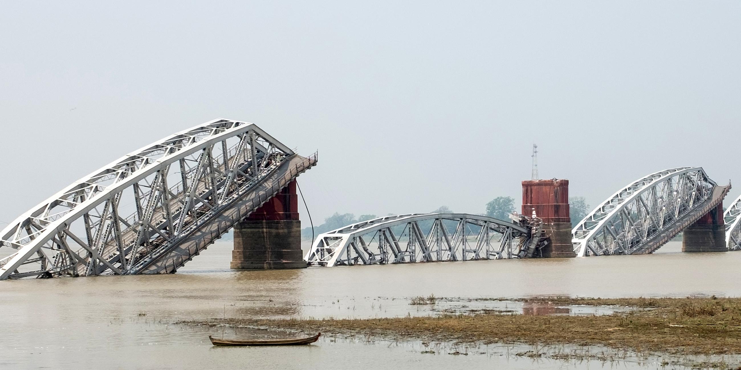 Eine in sich zusammengefallene Brücke über einem Fluss in Myanmar.