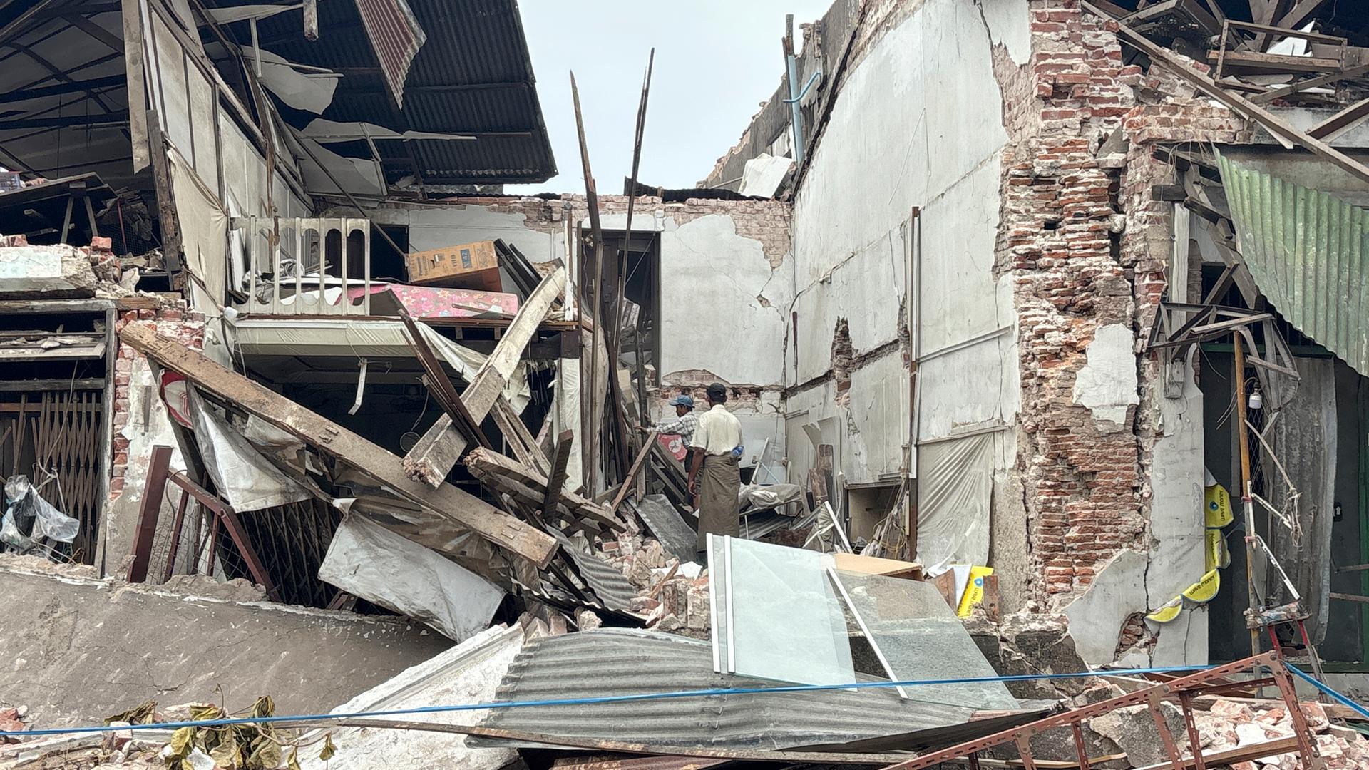 People clean debris from damaged buildings in the aftermath of an earthquake on March 28, in Naypyitaw, Myanmar