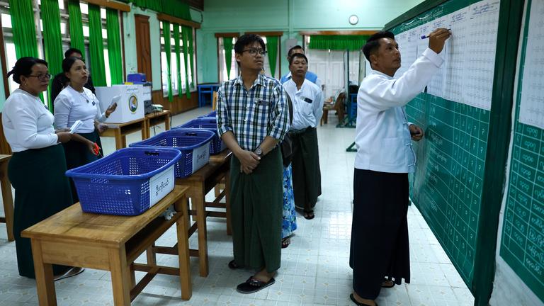 Myanmar electoral officers count early voting ballots after closing the first phase of general election at a polling station