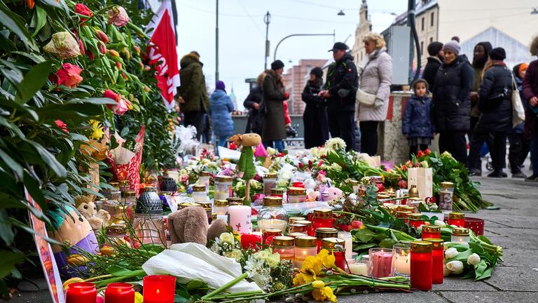 Menschen besuchen das mit Grabkerzen, Blumen und Kuscheltieren errichtete Denkmal für die Opfer, aufgenommen am 16.02.2025 in München