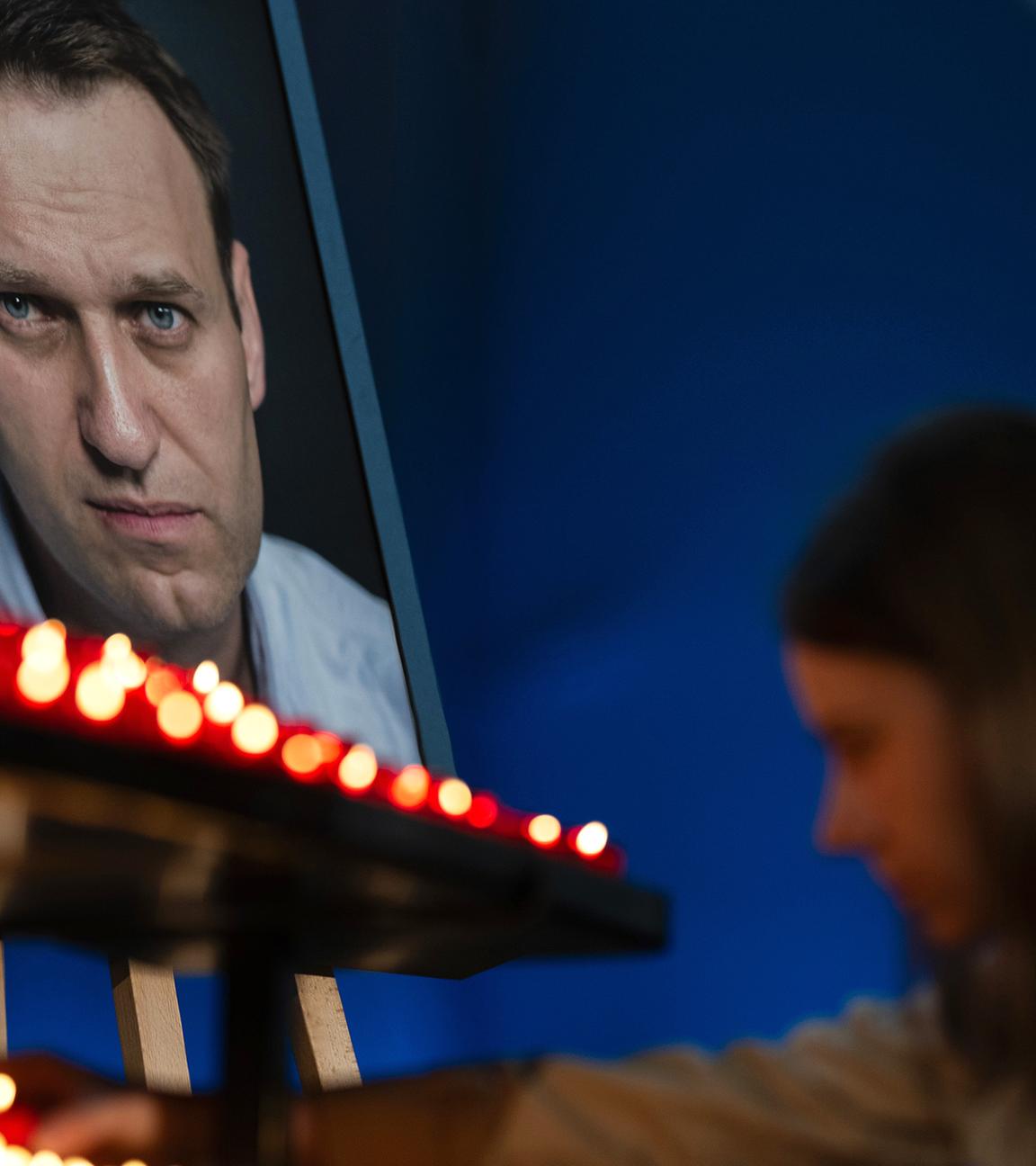 Ein Besucherin zündet zum Ende eines Gottesdiensts in der St. Marienkirche für den verstorbenen russischen Oppositionspolitiker Nawalny an dessen Geburtstag vor seinem Bild eine Kerze an