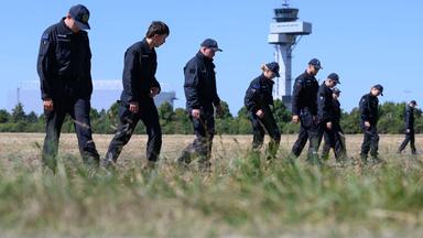 Einsatzkräfte der Polizei suchen ein Feld am Flughafen Leipzig/Halle nach Spuren ab, aufgenommen am 12.08.2026
