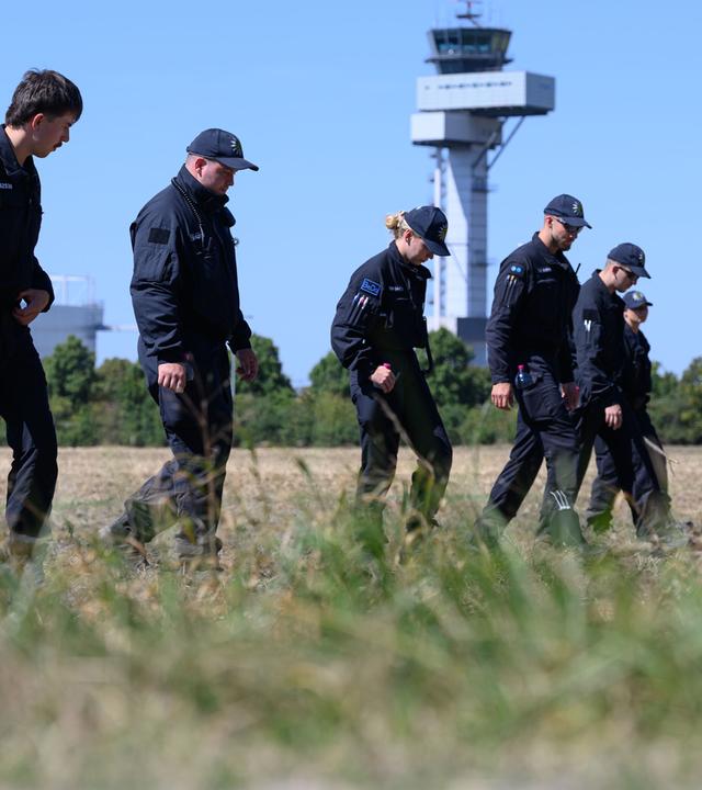Einsatzkräfte der Polizei suchen ein Feld am Flughafen Leipzig/Halle nach Spuren ab, aufgenommen am 12.08.2026