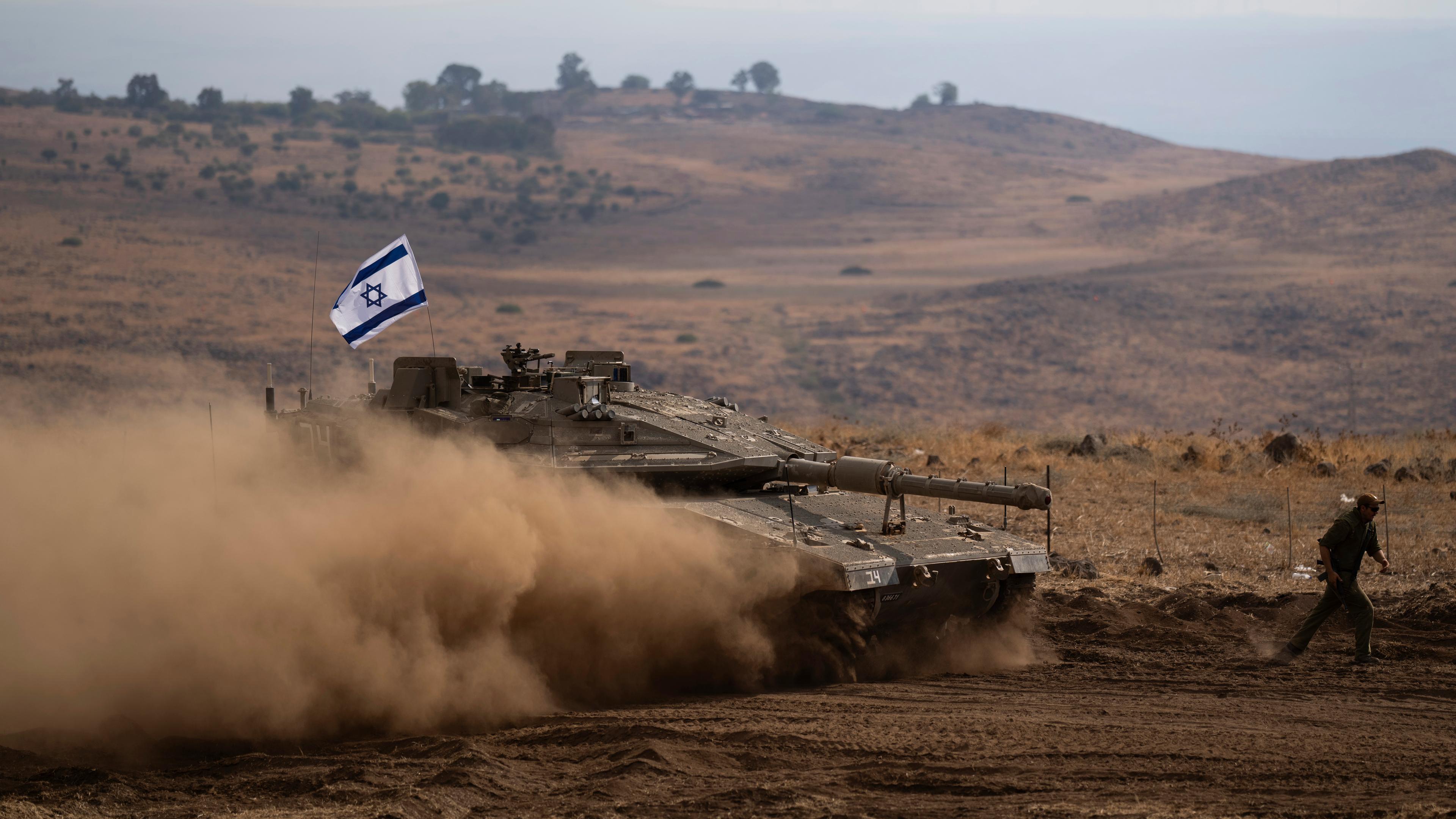 Ein Panzer mit einer israelischen Flagge auf dem Dach fährt zu einem Sammelplatz 