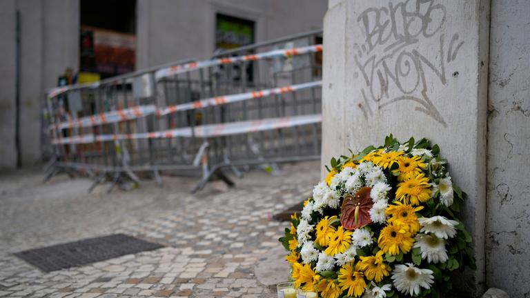 Ein Blumenkranz steht am Unfallort einer entgleisten und verunglückten Standseilbahn. 